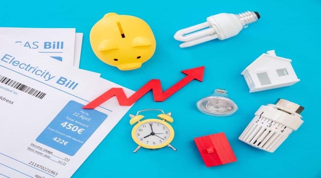 Living cost increase flat lay. Shopping cart utilities bills on blue background.